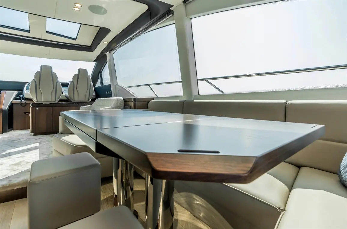 Interior of a modern yacht featuring a dining table, plush seating, and large windows, enhancing natural light and luxury.